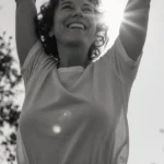 Femme souriante les bras levés vers le ciel, symbolisant l'espoir de retrouver l'amour.